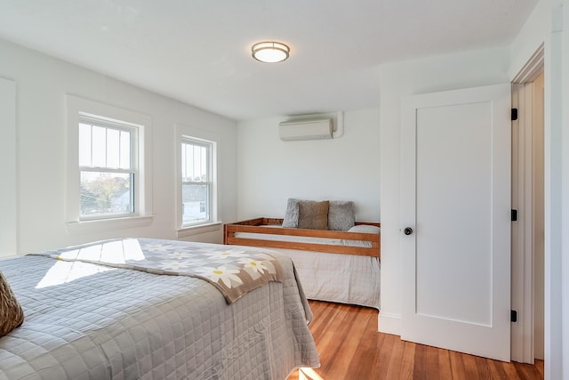 bedroom with a wall unit AC and wood finished floors