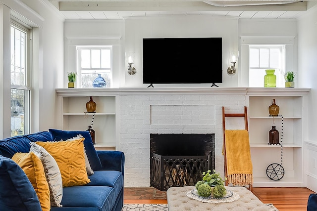 living room featuring a brick fireplace, crown molding, and wood finished floors