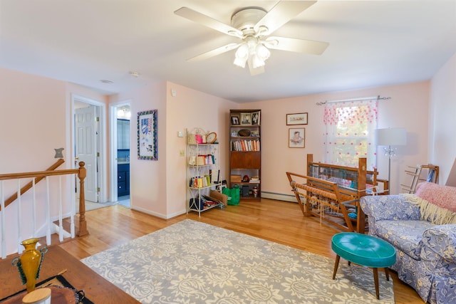 living room featuring ceiling fan, a baseboard radiator, baseboards, and wood finished floors