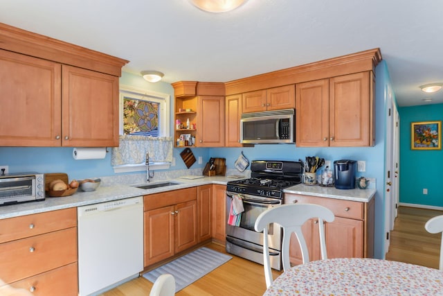 kitchen featuring open shelves, stainless steel appliances, light wood-style floors, and a sink