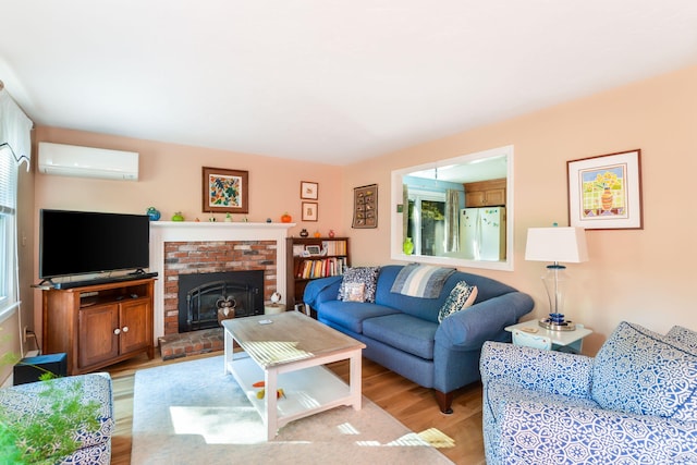 living room with a wall mounted air conditioner, light wood-style floors, a wealth of natural light, and a fireplace