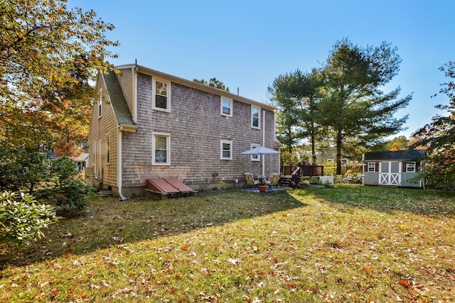 back of house with a yard, a storage shed, and an outdoor structure