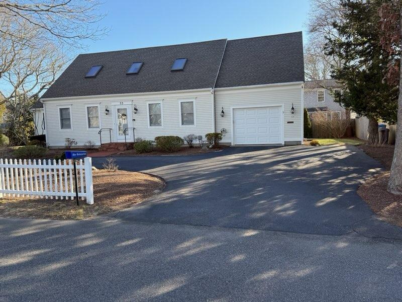 cape cod home featuring driveway, a garage, and fence