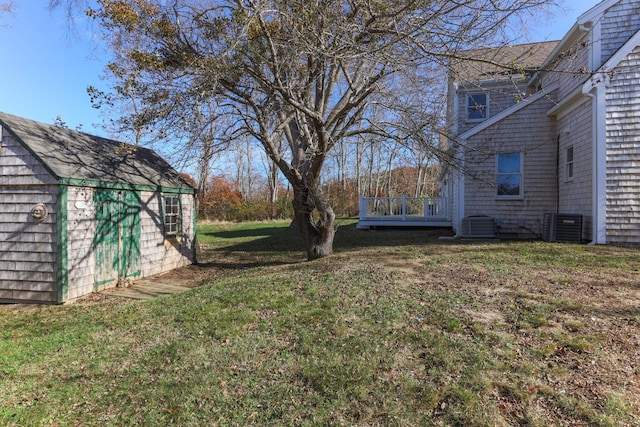 view of yard featuring a wooden deck, central AC unit, and a shed