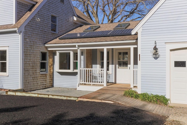 doorway to property featuring covered porch, a garage, and solar panels