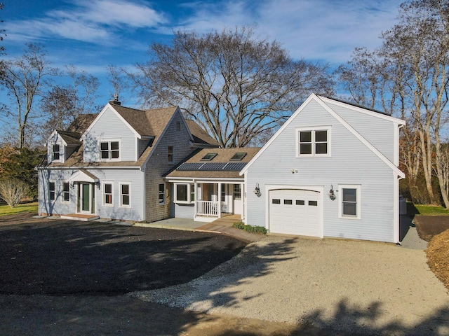 new england style home featuring covered porch and a garage