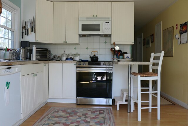 kitchen featuring light wood finished floors, white appliances, a toaster, and backsplash