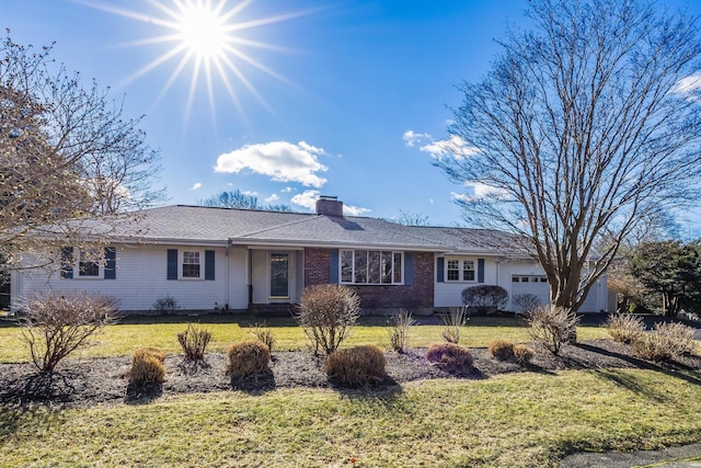 single story home with a garage, a chimney, a front lawn, and brick siding