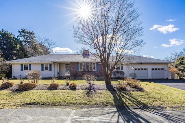 ranch-style home featuring aphalt driveway, brick siding, a chimney, a garage, and a front lawn