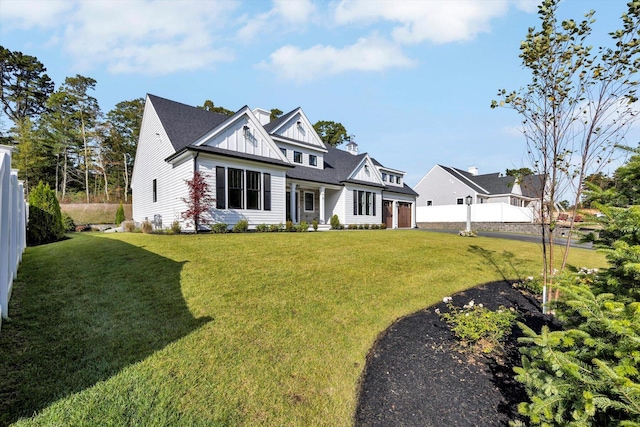 view of front facade featuring board and batten siding, a front yard, fence, and a chimney