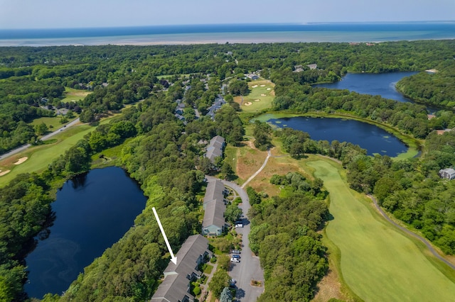 drone / aerial view with a view of trees, view of golf course, and a water view