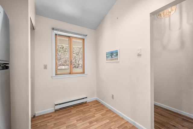 clothes washing area featuring baseboard heating, light wood finished floors, and baseboards