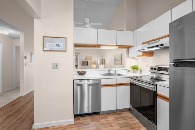 kitchen with light countertops, appliances with stainless steel finishes, under cabinet range hood, light wood-style flooring, and high vaulted ceiling