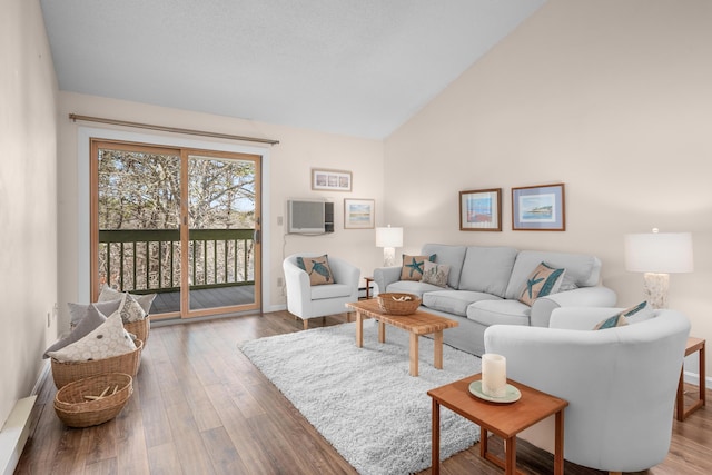 living area with high vaulted ceiling, a wall mounted AC, baseboards, and wood finished floors