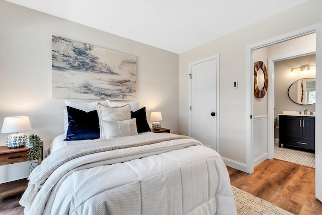 bedroom featuring wood finished floors, baseboards, and a sink