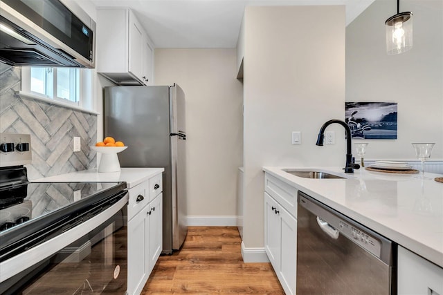 kitchen with stainless steel appliances, a sink, light wood-style flooring, light countertops, and white cabinets