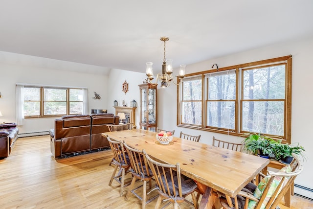 79 Pinewood Cir, Wellfleet, MA 02667 - dining room featuring a fireplace, light wood-type flooring, a baseboard heating unit, and an inviting chandelier