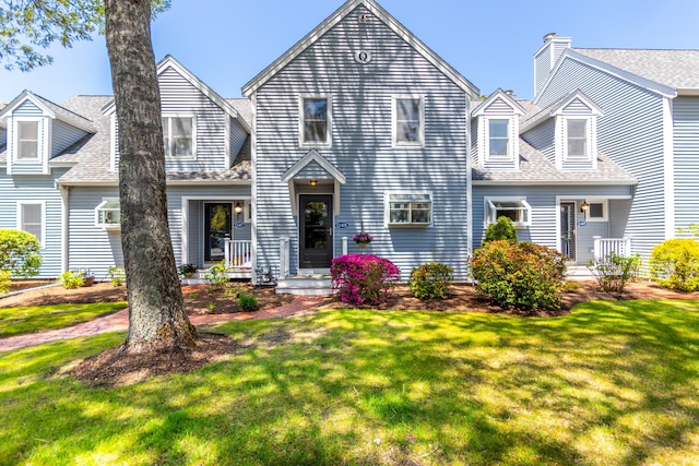 view of front facade with a front lawn and a shingled roof