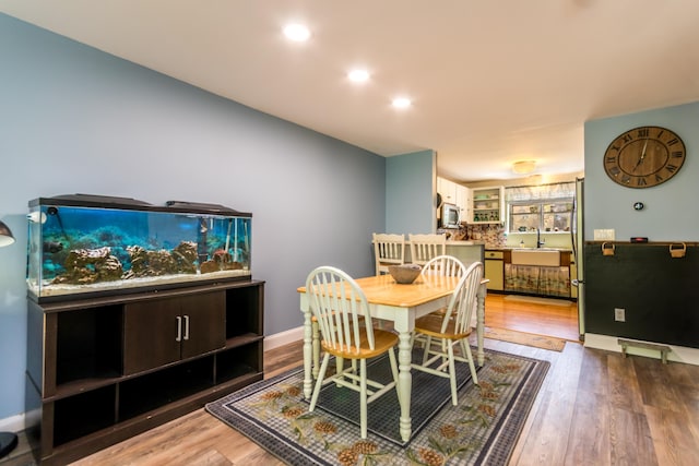 dining room featuring wood finished floors, baseboards, and recessed lighting