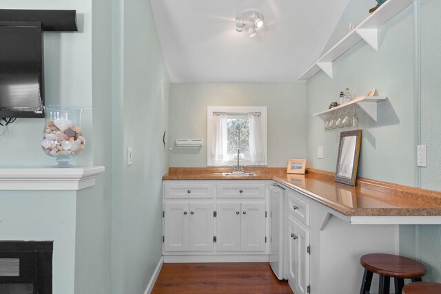 kitchen featuring a sink, open shelves, white cabinets, a breakfast bar area, and dark wood-type flooring