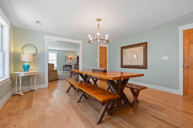 dining room featuring a chandelier, light wood finished floors, and baseboards