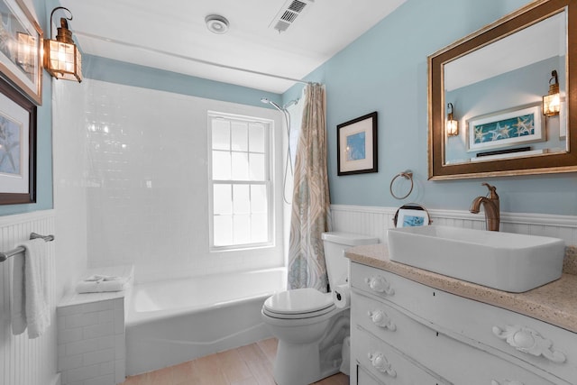 bathroom featuring a wainscoted wall, toilet, shower / tub combo with curtain, vanity, and wood finished floors