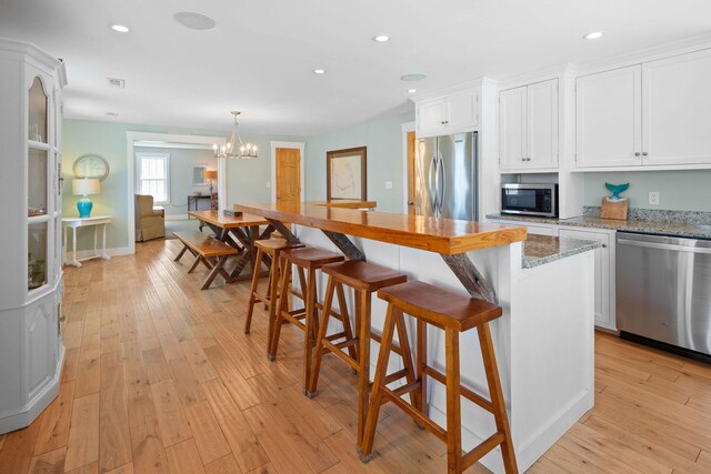 kitchen with stainless steel appliances, white cabinets, light wood-style flooring, recessed lighting, and a center island