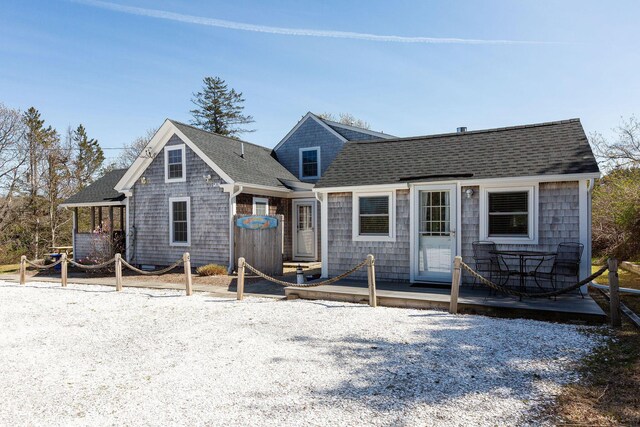 rear view of property with a deck and a shingled roof
