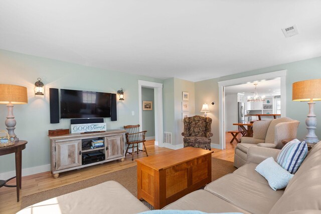 living room featuring light wood finished floors, a chandelier, and baseboards