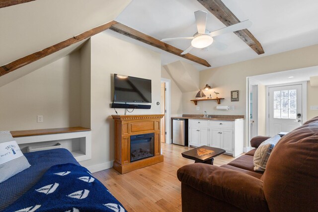 living area with wet bar, light wood-style flooring, and ceiling fan