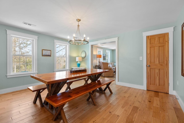 dining area with a chandelier, baseboards, and light wood-style flooring