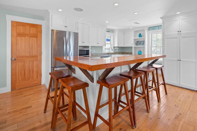 kitchen featuring stainless steel appliances, open shelves, white cabinets, light wood finished floors, and recessed lighting