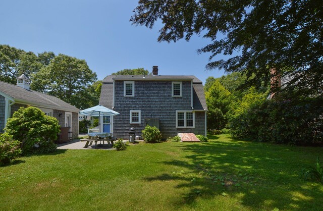 110 Teaticket Path, East Falmouth, MA 02536 - rear view of house featuring a patio area, a lawn, and a chimney