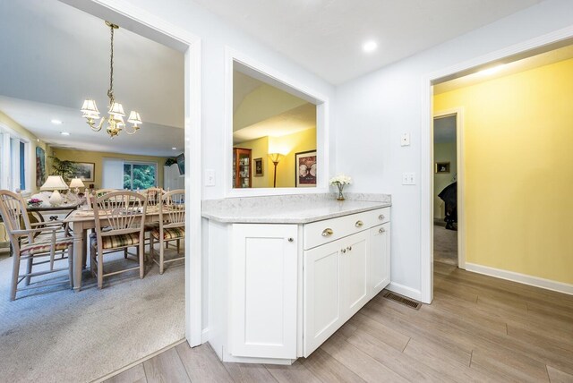 37 Pine Hill Blvd, Mashpee, MA 02649 - kitchen with a chandelier, light wood finished floors, white cabinetry, light countertops, and hanging light fixtures