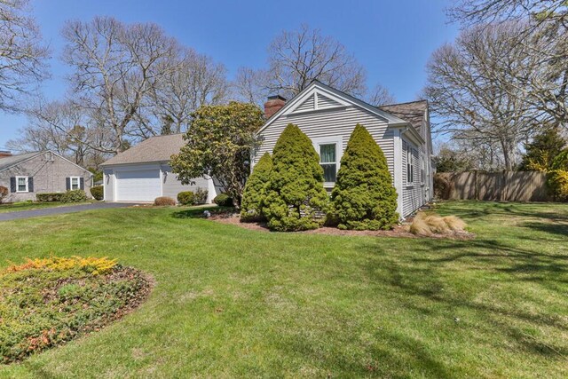 56 Fairwood Rd, South Yarmouth, MA 02664 - view of front of property with a detached garage, a chimney, a front lawn, and fence