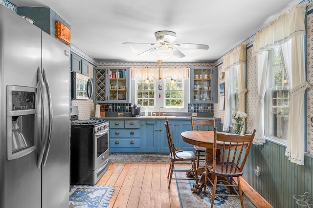 kitchen with sink, blue cabinetry, tasteful backsplash, light hardwood / wood-style floors, and stainless steel appliances