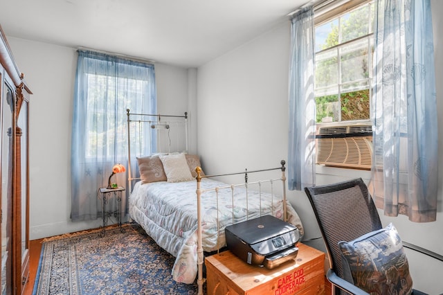 bedroom featuring hardwood / wood-style flooring, cooling unit, and multiple windows