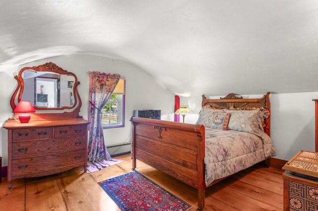 bedroom with light hardwood / wood-style floors, baseboard heating, and lofted ceiling