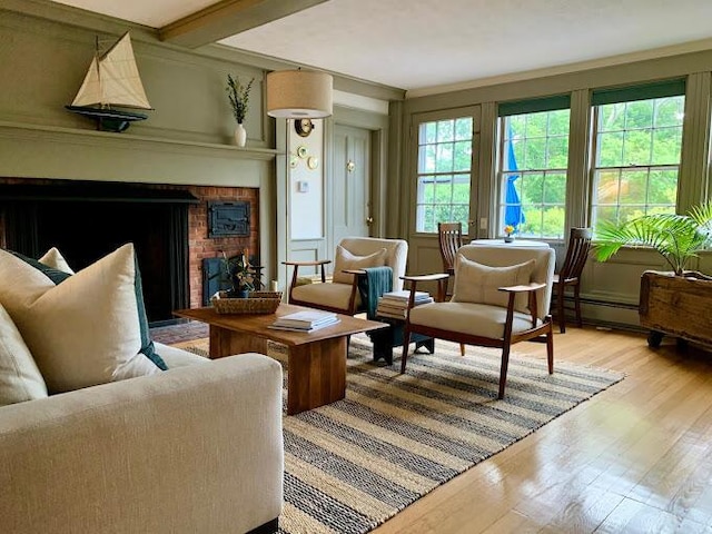 sitting room with light wood-type flooring, beam ceiling, a brick fireplace, and ornamental molding