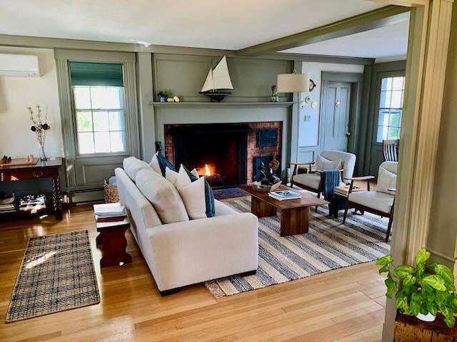 living room featuring a wall mounted air conditioner, light hardwood / wood-style flooring, and a wealth of natural light