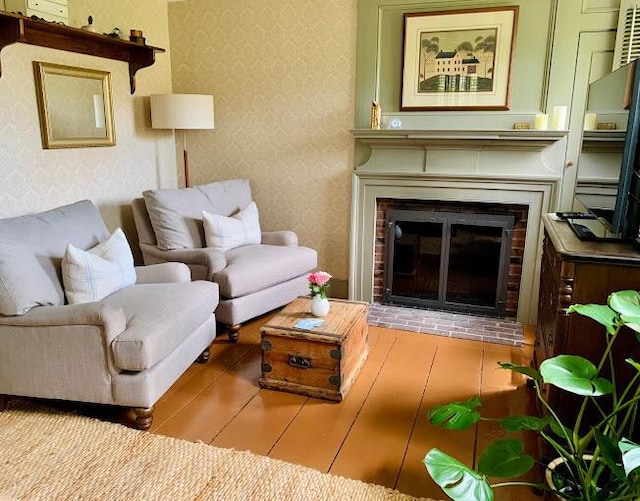 living room featuring hardwood / wood-style flooring and a brick fireplace