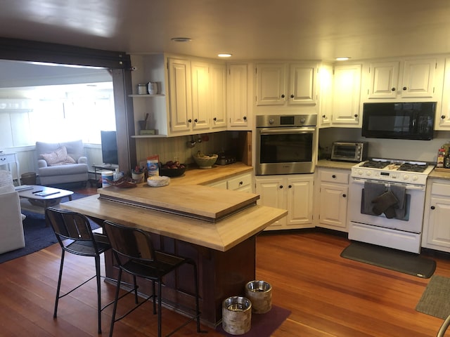 kitchen with dark hardwood / wood-style floors, stainless steel oven, white cabinets, and gas range gas stove