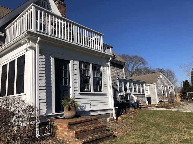 view of property exterior featuring a balcony and a yard