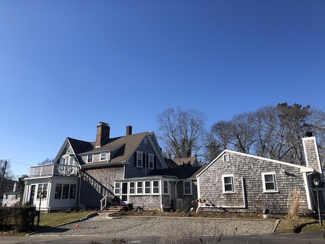 back of house featuring central air condition unit, a balcony, and a sunroom