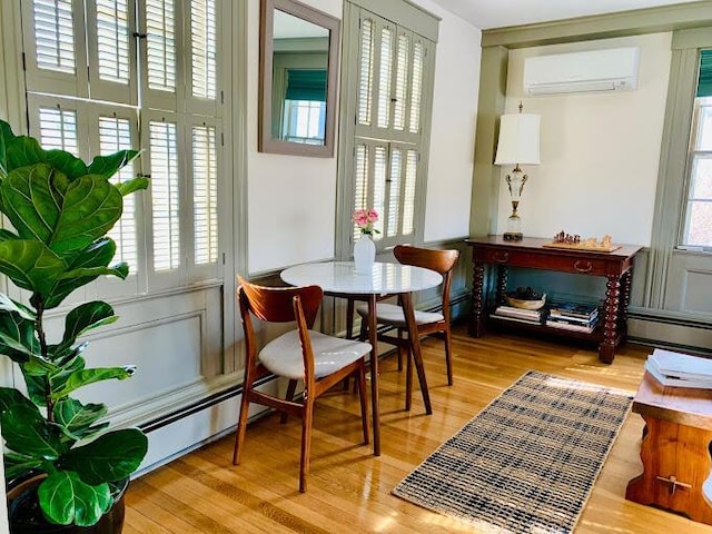 living area with hardwood / wood-style flooring, an AC wall unit, and a healthy amount of sunlight