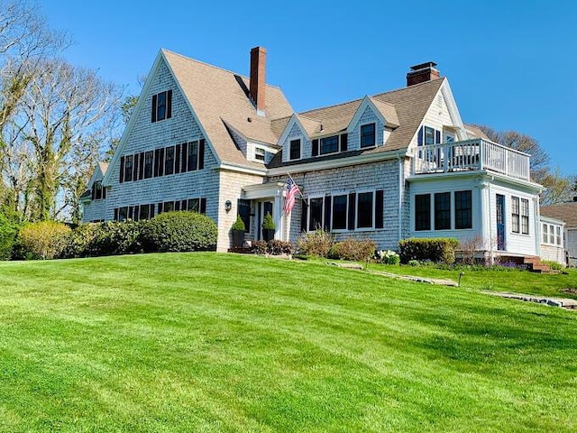 view of front of house featuring a balcony and a front yard