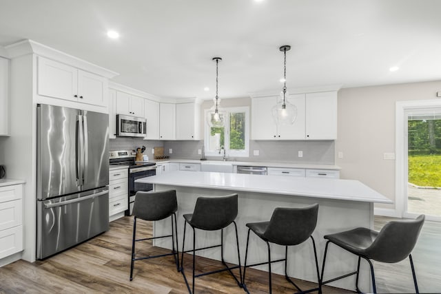 218 Center St, South Dennis, MA 02660 - kitchen with appliances with stainless steel finishes, a kitchen bar, light countertops, decorative backsplash, and healthy amount of natural light