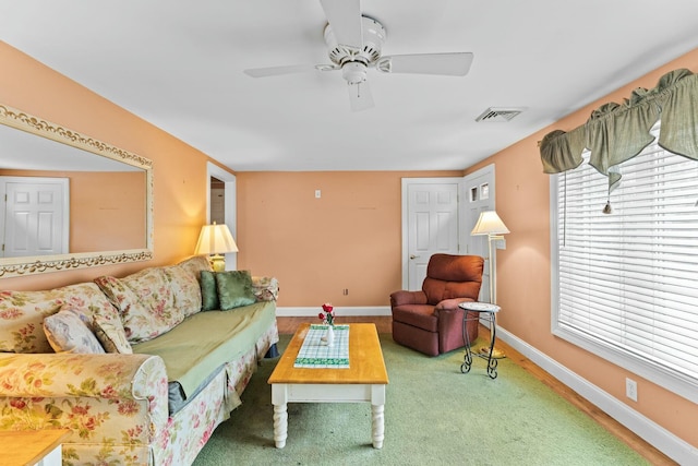 living room with baseboards, visible vents, and ceiling fan