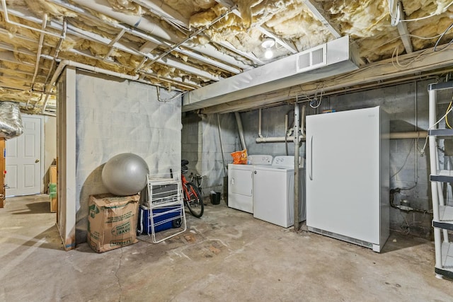 unfinished basement featuring washer and dryer, freestanding refrigerator, and visible vents