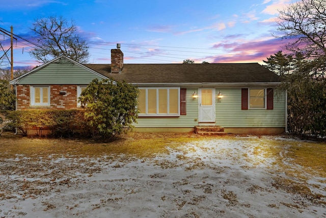 ranch-style house with entry steps, a chimney, and brick siding